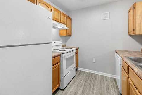 A kitchen with a white refrigerator, white oven, and wooden cabinets.