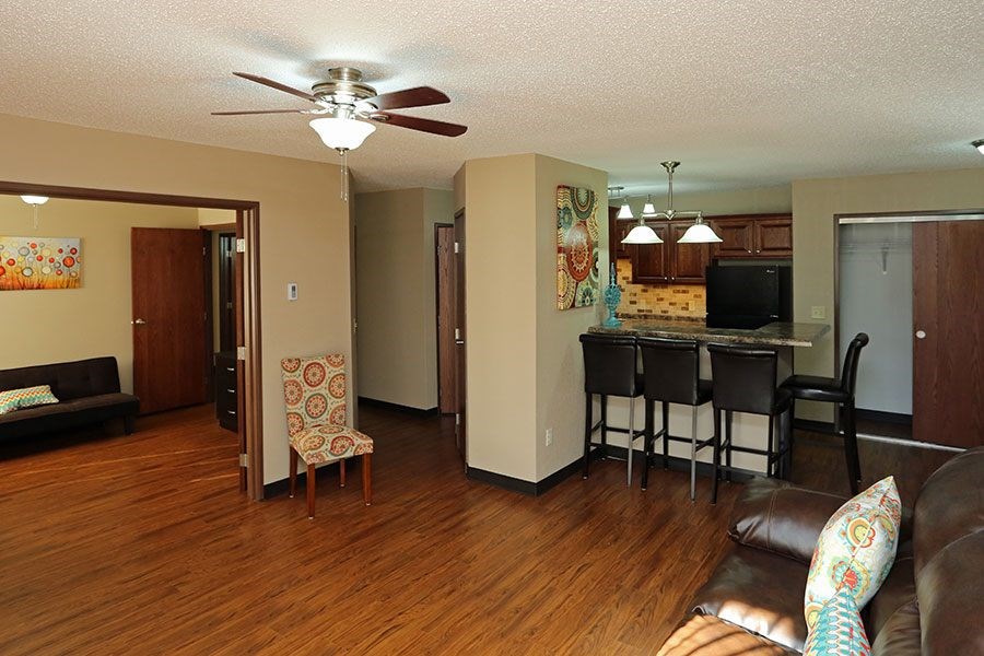 A living room with a brown leather couch and a wooden floor.