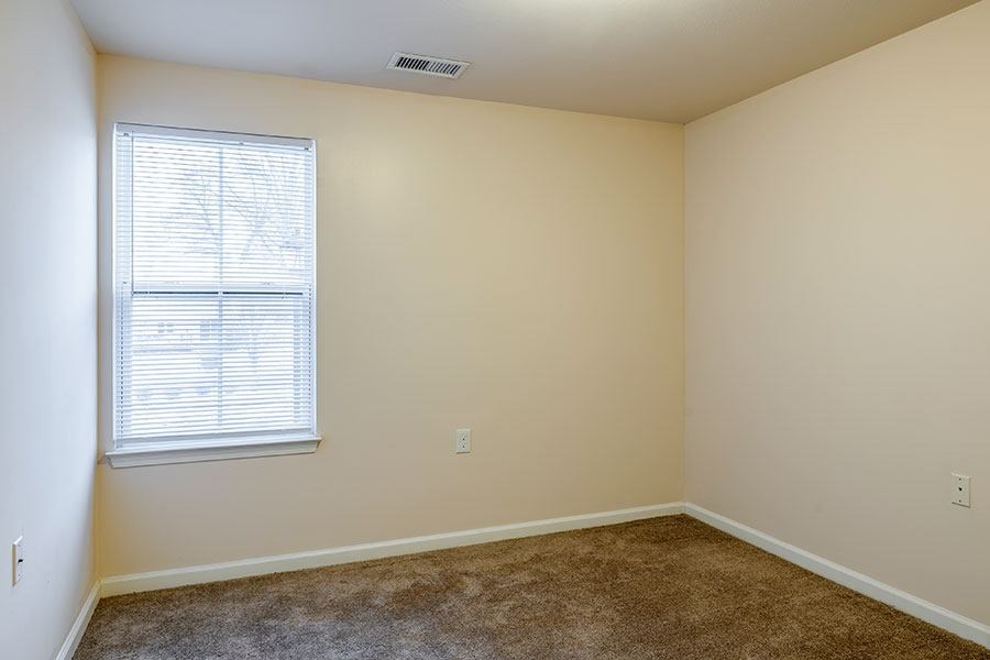 A room with a window and carpeted floor.