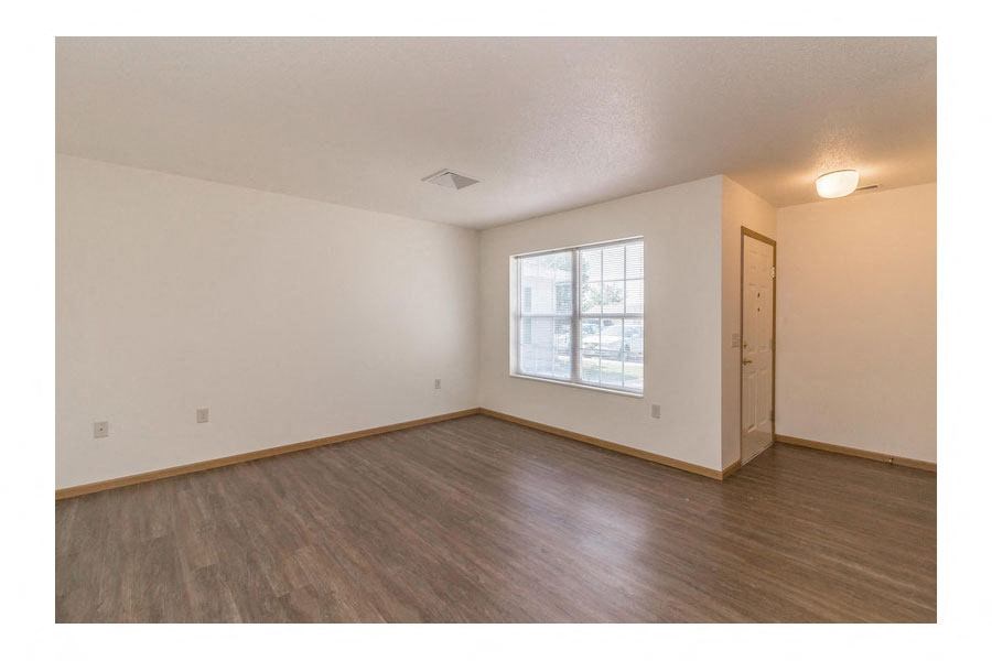 an empty living room with wood floors and a window