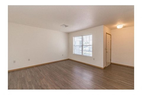an empty living room with wood floors and a window