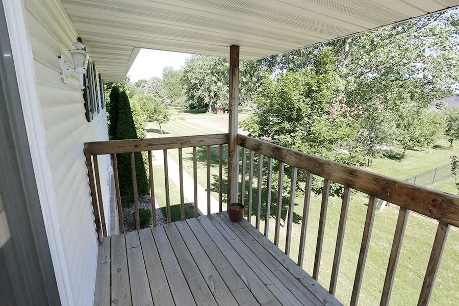 a porch with a view of a field and trees