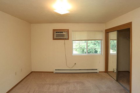 an empty living room with a window and a air conditioner
