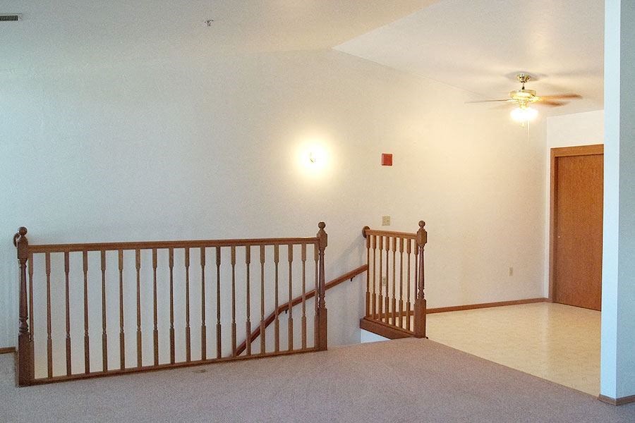 a living room with a staircase and a ceiling fan