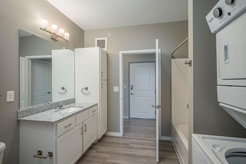 A bathroom with a white vanity and a white washer and dryer.