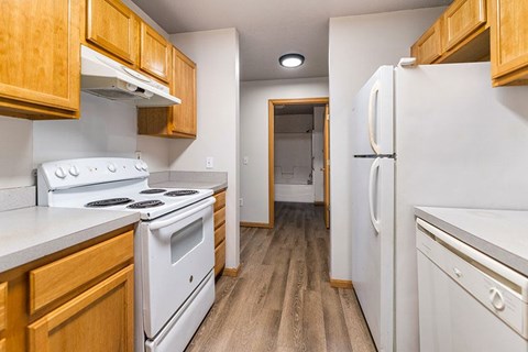 A kitchen with white appliances and wooden cabinets.