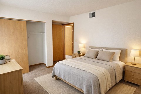 A bedroom with a bed, nightstand, and a plant on the nightstand.