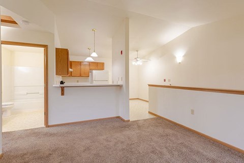 an empty living room with a kitchen and a toilet