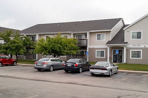 three cars parked in a parking lot in front of an apartment building