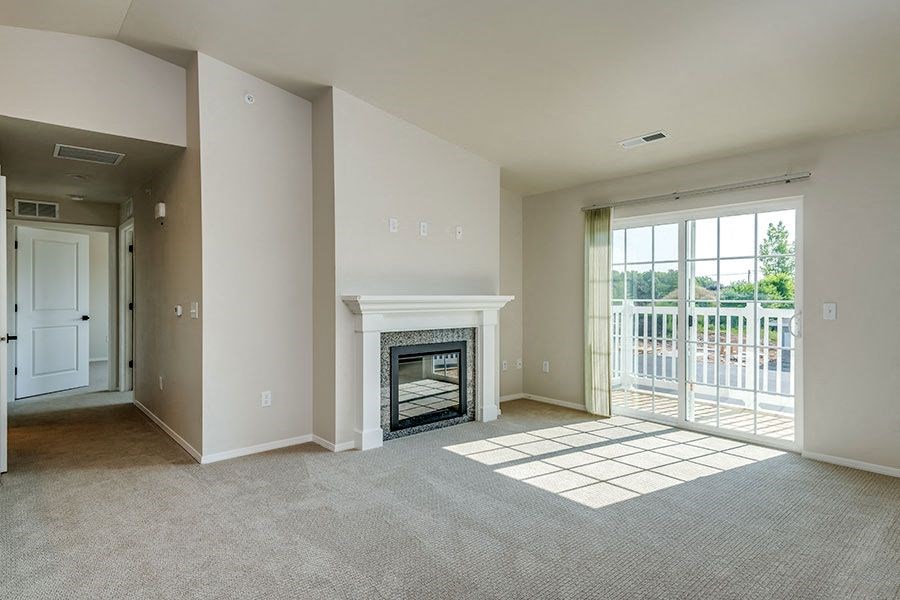 an empty living room with a fireplace and a door to a balcony