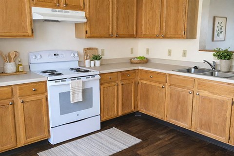 A white stove is in a kitchen with wooden cabinets.