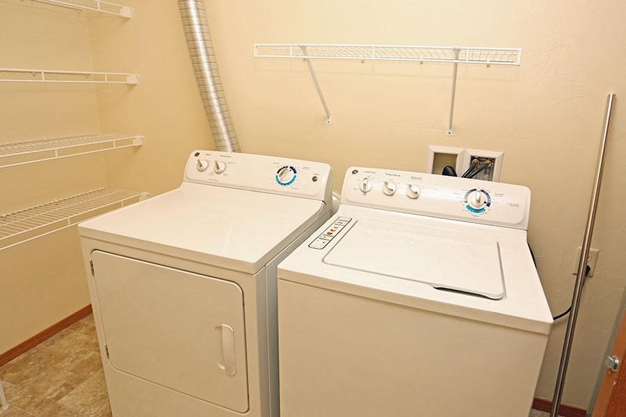 two washers and dryers in a room with a closet
