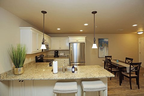 A kitchen with a granite countertop and a dining table with chairs.