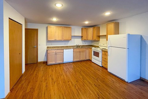 A kitchen with wooden floors and white appliances.