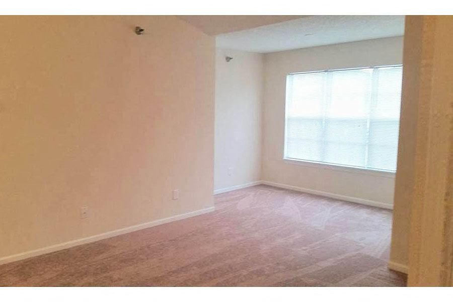 an empty living room with a window and wooden floors