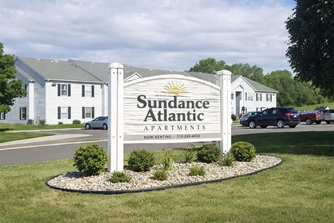 A sign for Sudance Atlantic Apartments is in front of some houses.