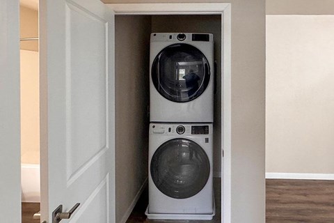 A white washing machine is in a small space next to a door.