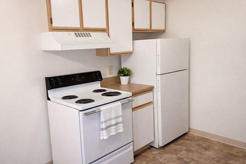 A small kitchen with a white stove and refrigerator.