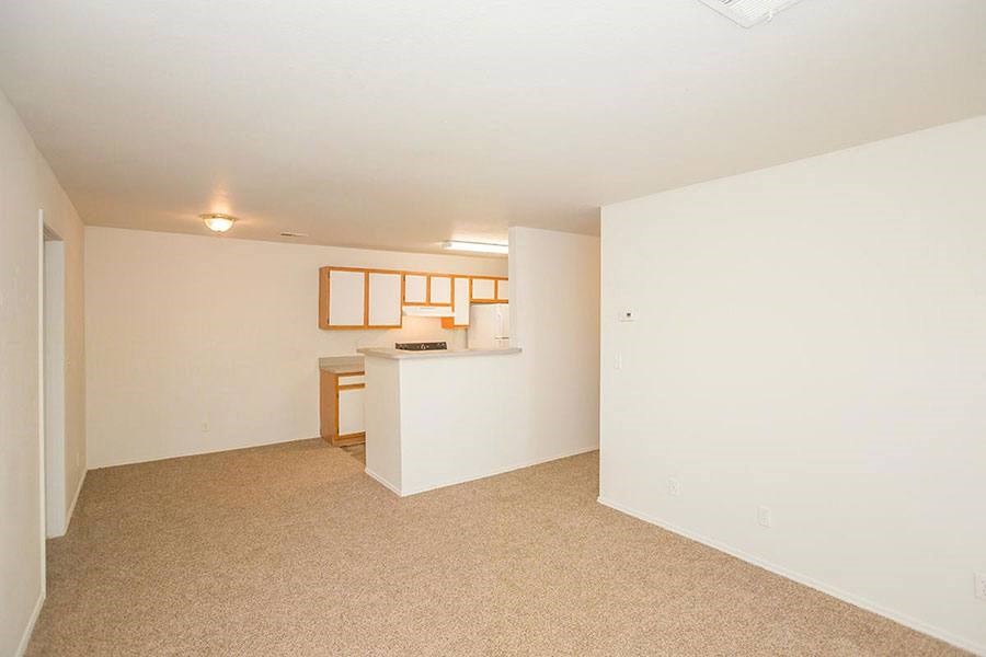A small white reception desk with a wooden chair sits in a room with a carpeted floor.