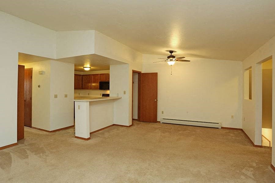 A spacious living room with a kitchen in the background.