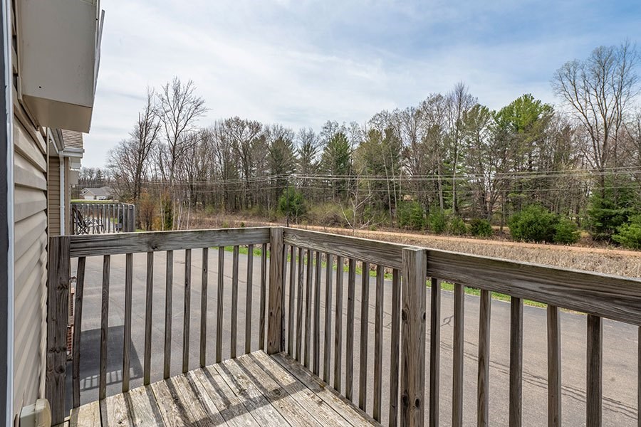 A wooden deck with a railing and a view of trees.