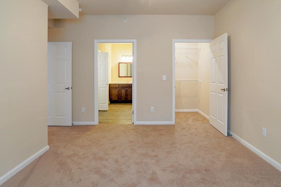 an empty living room with two doors and a bathroom
