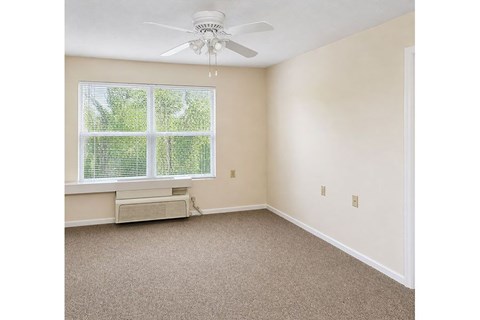A room with a ceiling fan and a window with blinds.
