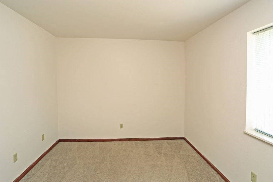 an empty room with a carpet and a window