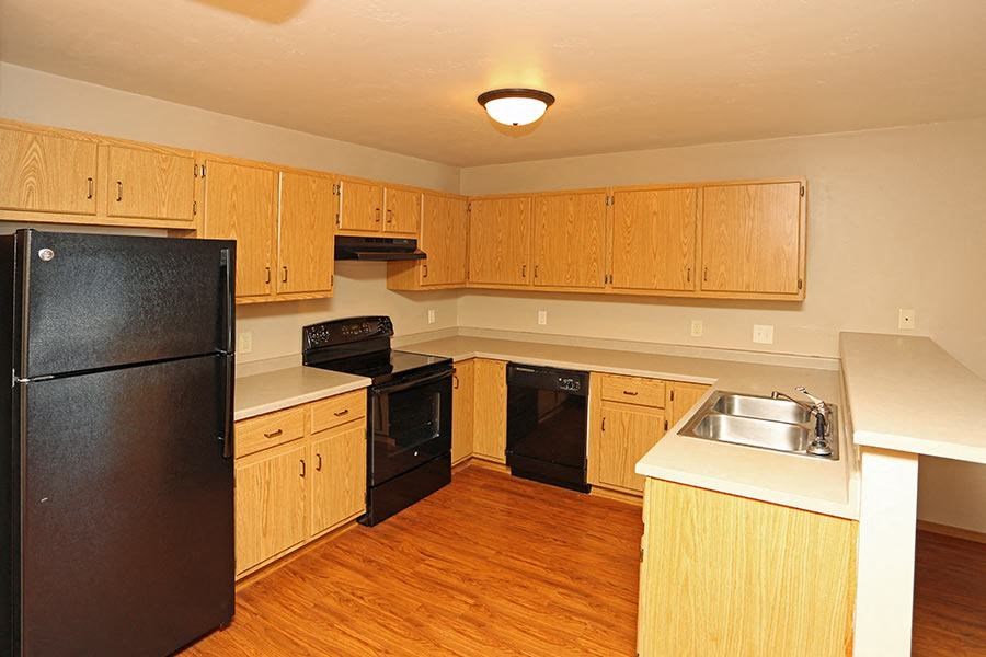 an empty kitchen with black appliances and wooden cabinets