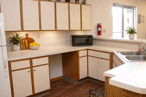 A kitchen with white cabinets and a black microwave.