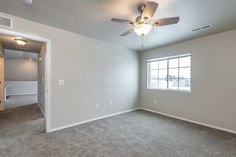 an empty living room with a ceiling fan