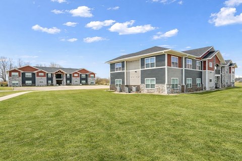 A large grassy field in front of a two story apartment building.