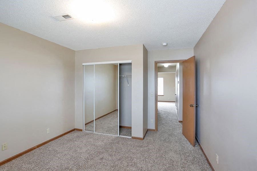 an empty bedroom with a mirrored closet