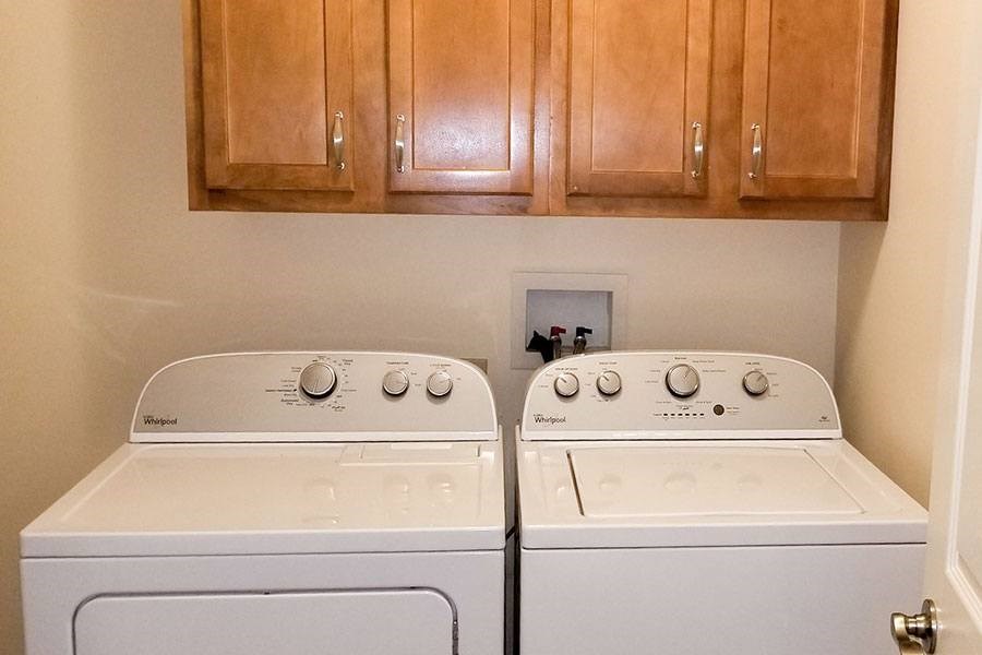 Two white front loading washing machines in a laundry room.
