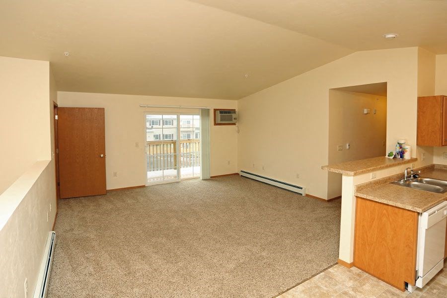 A spacious living room with a kitchenette and a window.