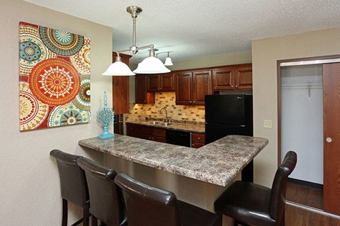 A kitchen with a black fridge and a granite counter.