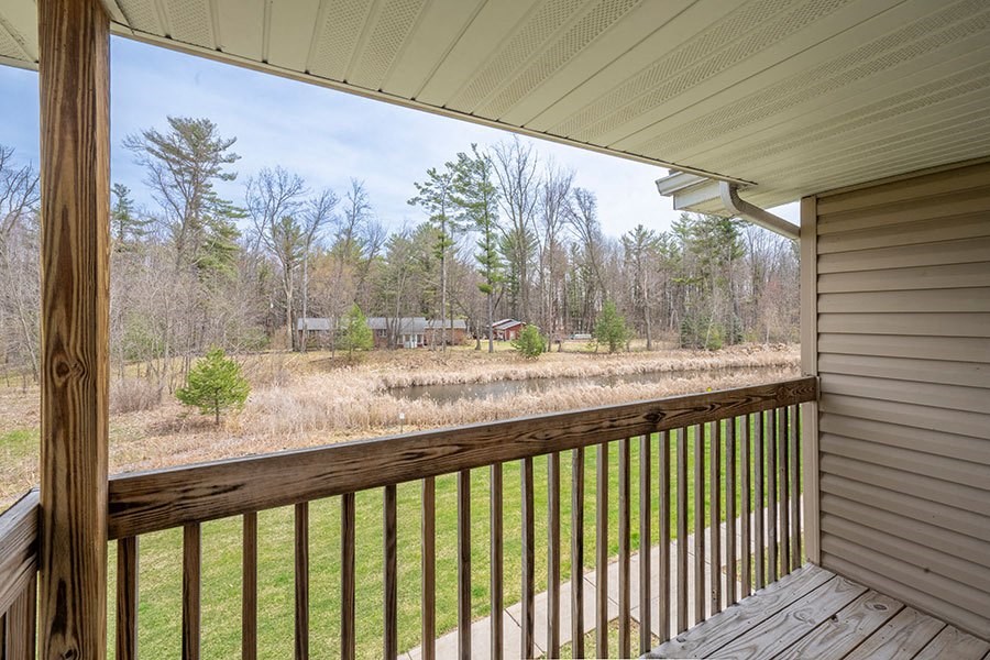 A wooden deck overlooks a grassy area with trees in the distance.