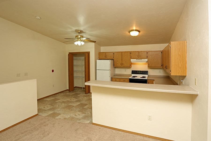 an empty kitchen with a white counter and a ceiling fan
