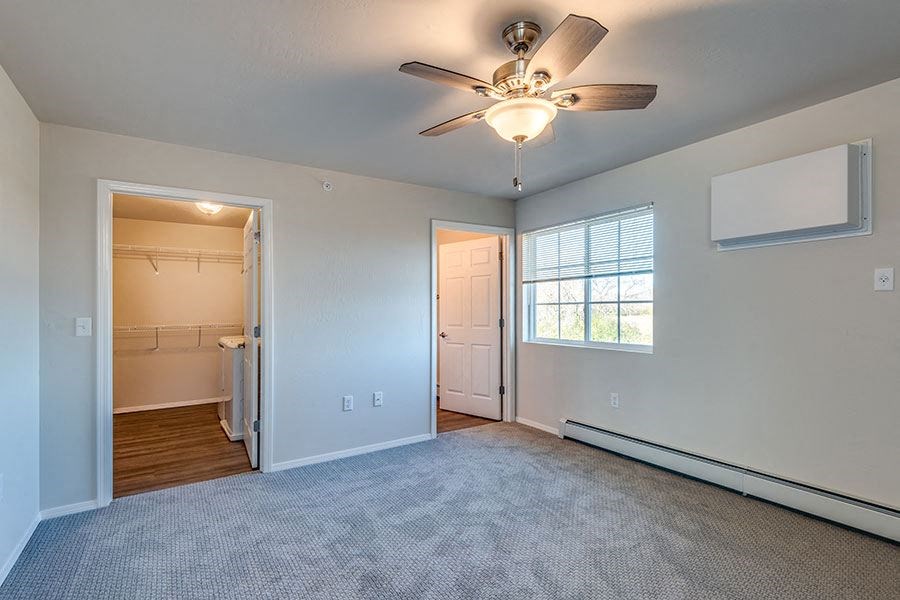 an empty living room with a ceiling fan and a closet