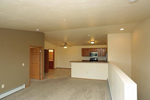 an empty living room and a kitchen with a counter top