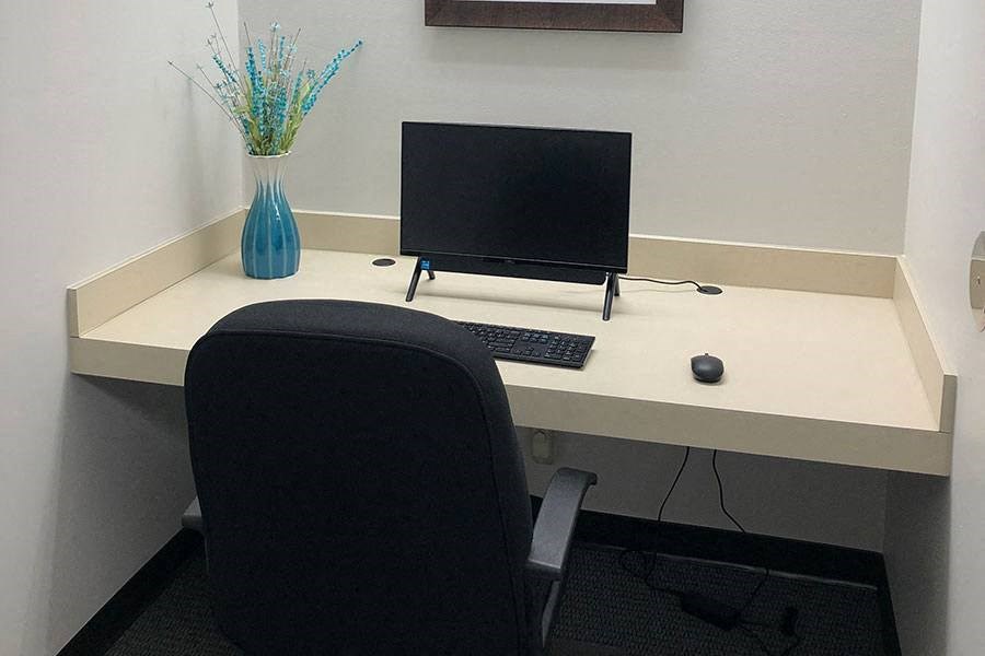 a desk with a computer monitor and a chair