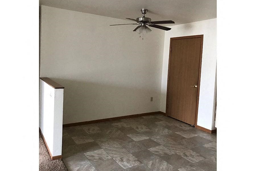 an empty room with a ceiling fan and a door