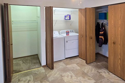 A laundry room with a washer and dryer and a coat hanging up.