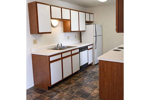 A kitchen with a white counter top and brown cabinets.