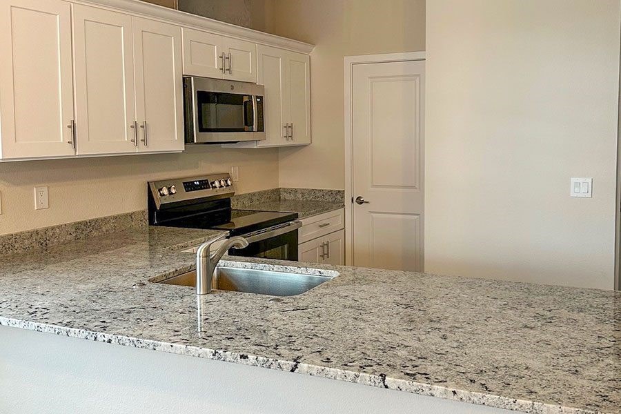 A kitchen with granite countertops and white cabinets.
