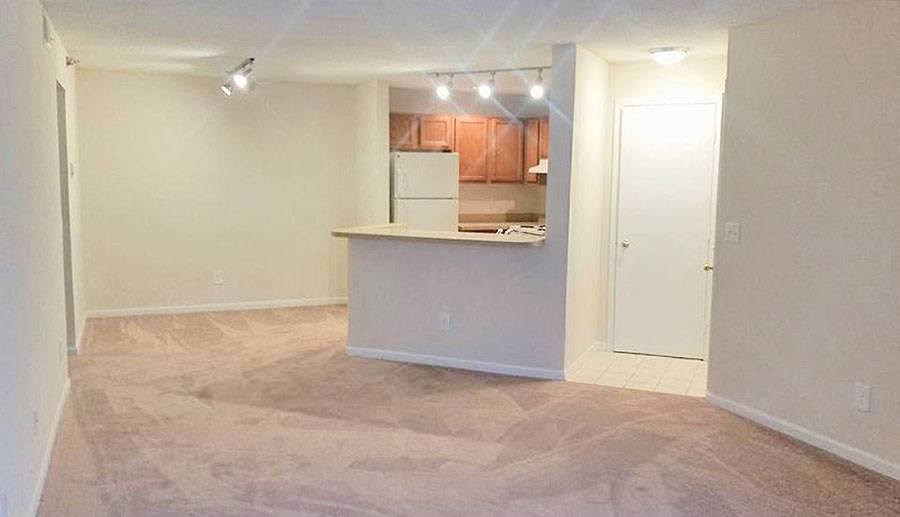 an empty living room with a kitchen in it
