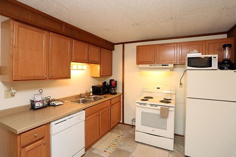 A kitchen with white appliances and wooden cabinets.