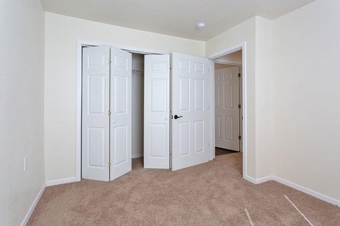 A room with white doors and carpeted floor.