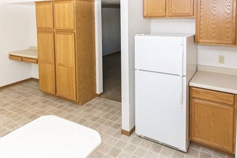 an empty kitchen with a white refrigerator and cabinets