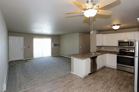 an empty kitchen and living room with a ceiling fan